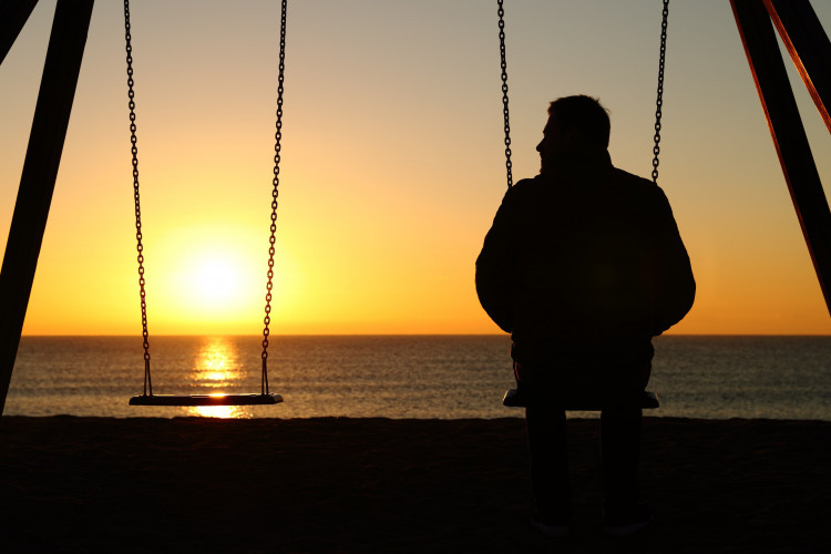 Mann auf einer Schaukel vor dem Meer